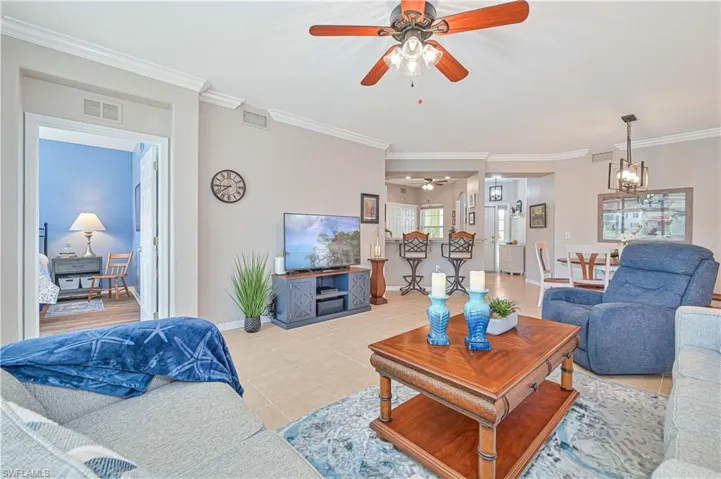 Tiled living area with ornamental molding and ceiling fan