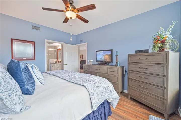 Bedroom with ceiling fan, connected bathroom, and light wood-style flooring