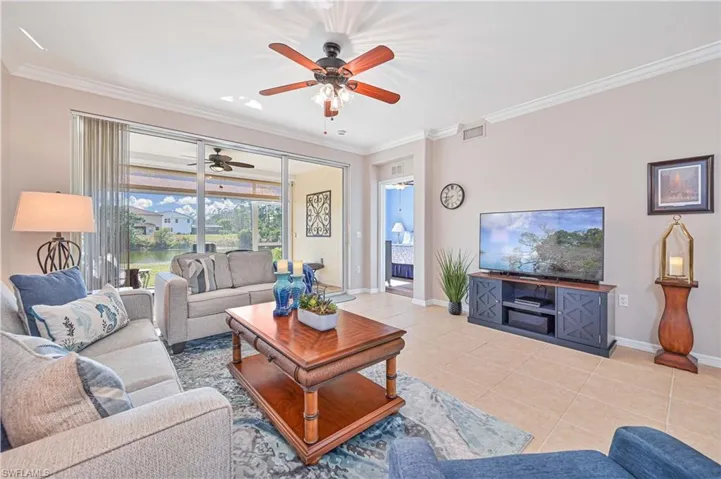 Living room with ornamental molding, light tile patterned floors, and a ceiling fan