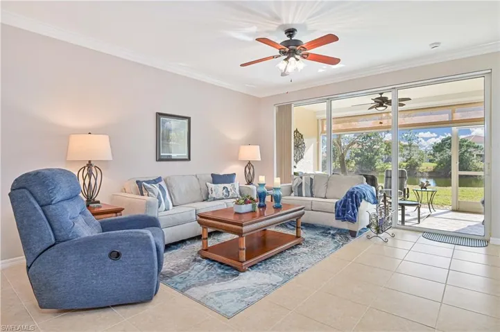 Tiled living room featuring ornamental molding, ceiling fan, and a water view
