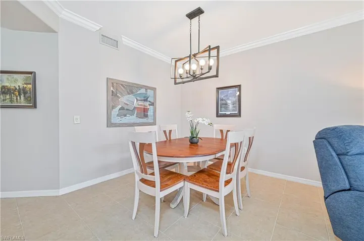 Dining room with ornamental molding, light tile patterned floors, and a chandelier