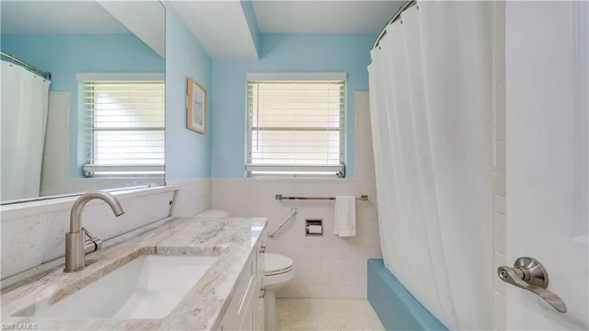 Extra Full bath with toilet, tile walls, plenty of natural light, vanity, and shower / bath combo.