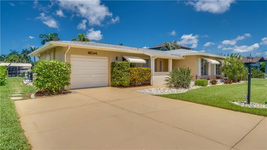 Ranch-style home with stucco siding, an attached garage and extended concrete driveway.