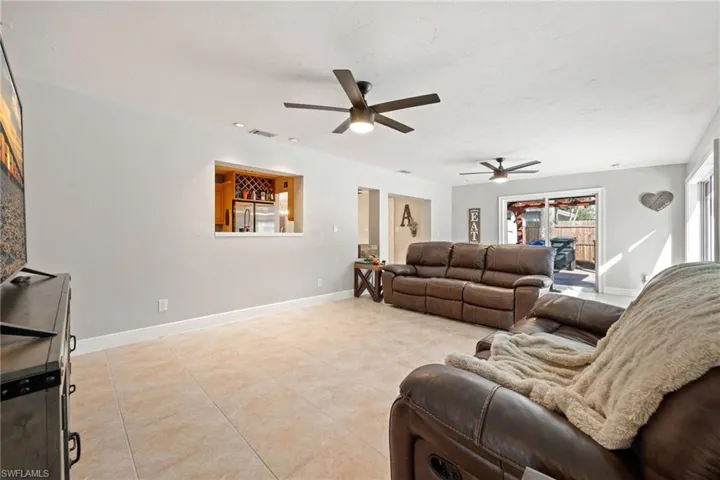 Living area with ceiling fan and light tile patterned flooring