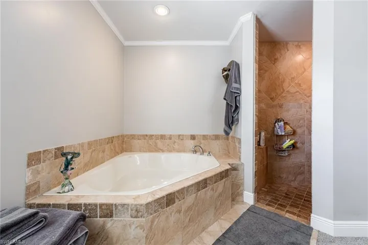 Full bath with a bath, ornamental molding, a walk in shower, and tile patterned flooring
