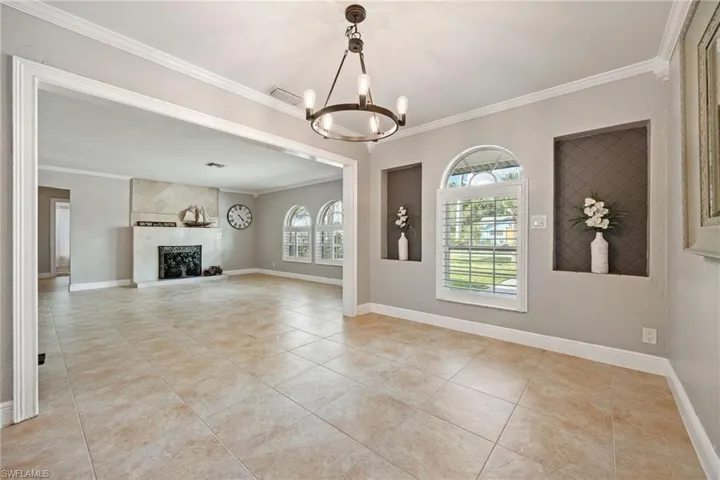 Unfurnished living room featuring ornamental molding, a fireplace, light tile patterned floors, and a chandelier