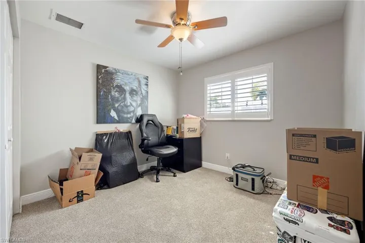 Carpeted home office with baseboards and a ceiling fan