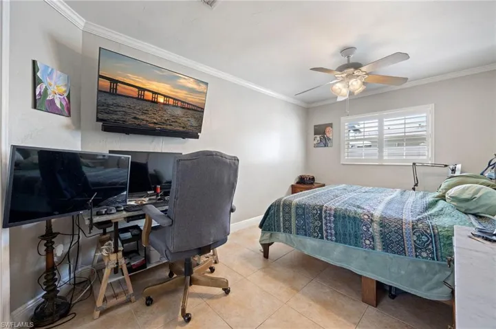 Bedroom with crown molding, an office area, a ceiling fan, and tile patterned floors