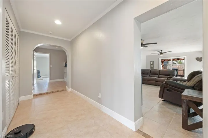 Hall with light tile patterned floors, arched walkways, and crown molding