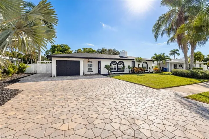 Ranch-style home with decorative driveway, a garage, stucco siding, and a chimney