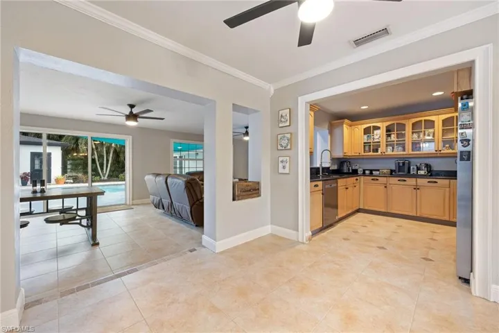 Kitchen with glass insert cabinets, open floor plan, crown molding, light tile patterned floors, and appliances with stainless steel finishes