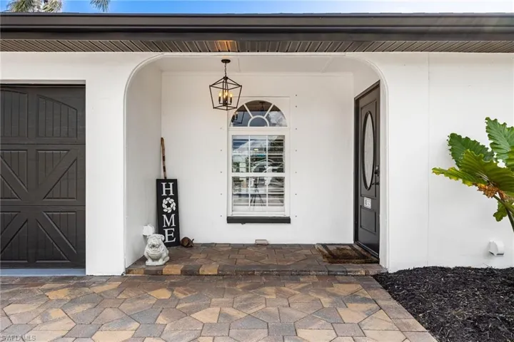 Entrance to property with covered porch, stucco siding, and a garage