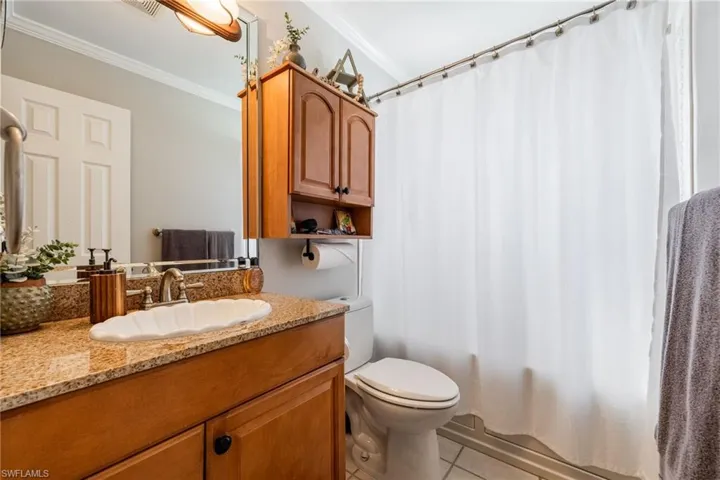 Full bath with vanity, crown molding, light tile patterned floors, and shower / bath combo