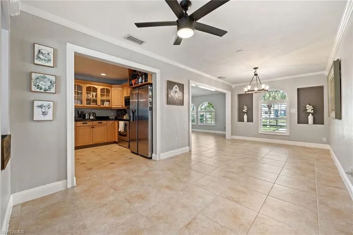 Kitchen with dark countertops, ornamental molding, stainless steel appliances, ceiling fan, and open floor plan