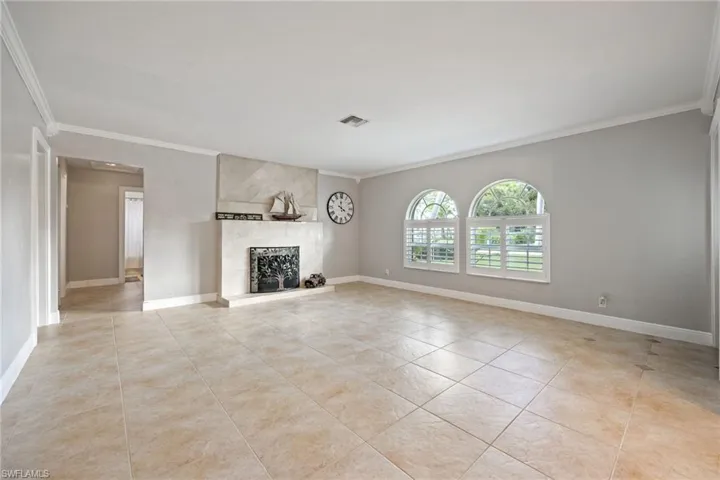Unfurnished living room featuring crown molding, a large fireplace, and light tile patterned floors