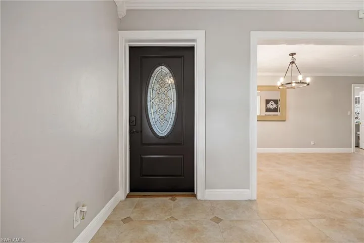 Entryway featuring crown molding, a chandelier, and light tile patterned floors