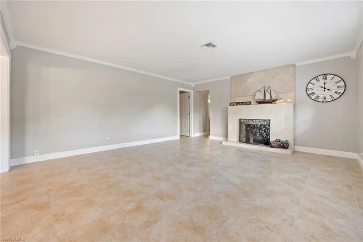 Unfurnished living room featuring crown molding, a fireplace, and light tile patterned flooring