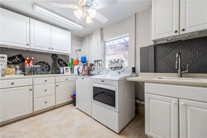 Laundry room with cabinet space, washer and dryer, light tile patterned floors, and a ceiling fan
