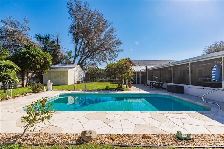 View of pool with a patio, a sunroom, a lawn, and a storage unit