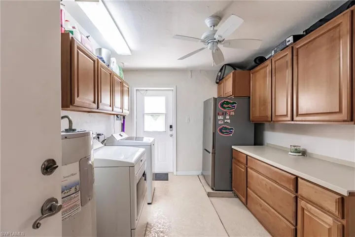 Laundry room featuring ceiling fan, washing machine and clothes dryer, water heater, and cabinets