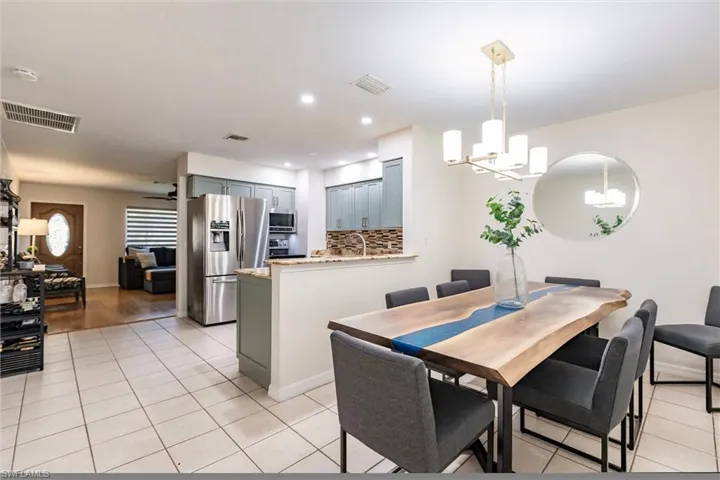 Tiled dining area featuring ceiling fan with notable chandelier and sink