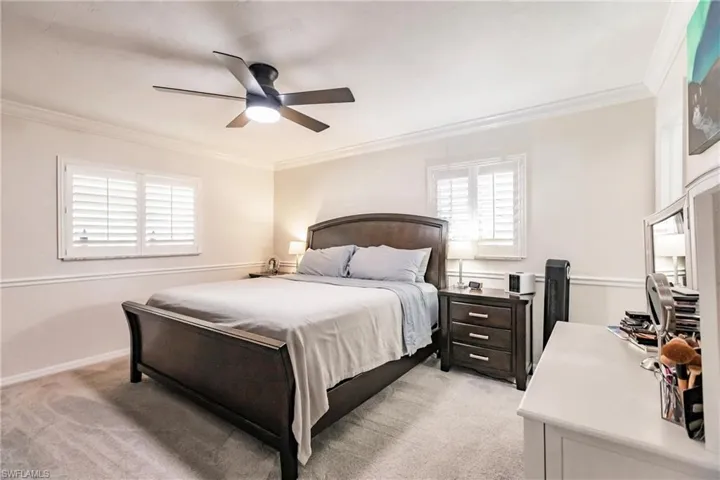 Bedroom featuring ornamental molding, light colored carpet, and ceiling fan