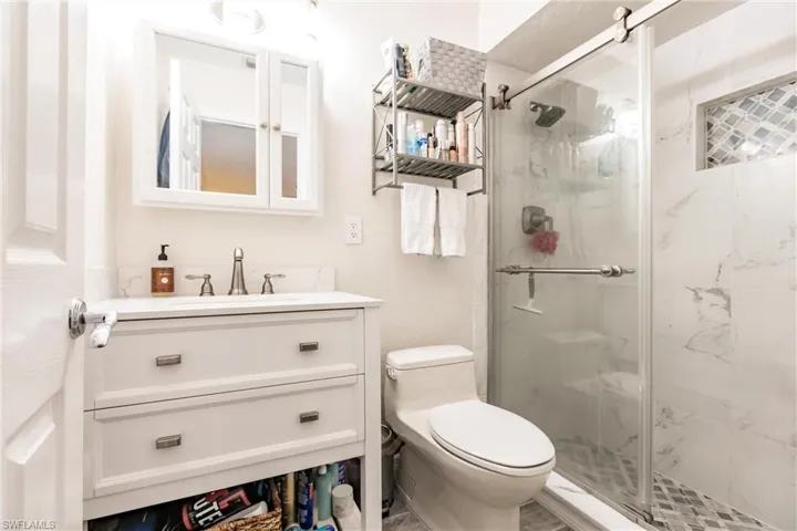 Bathroom featuring walk in shower, vanity, and toilet