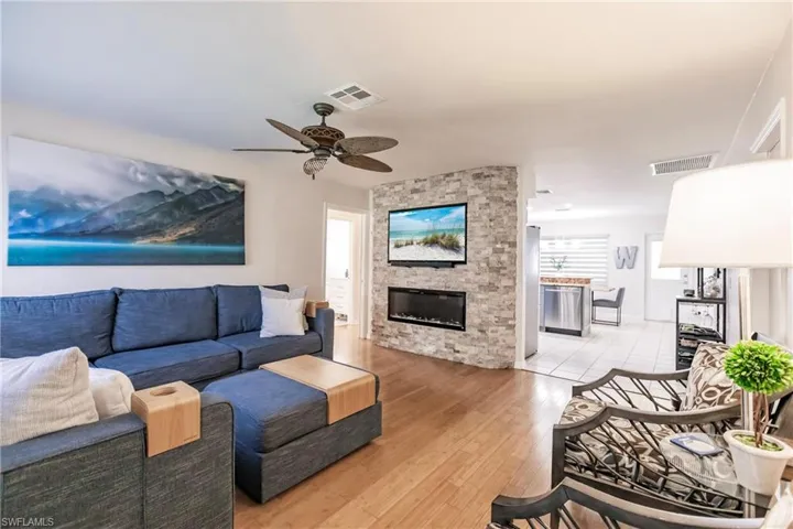 Living room with a fireplace, hardwood / wood-style flooring, and ceiling fan