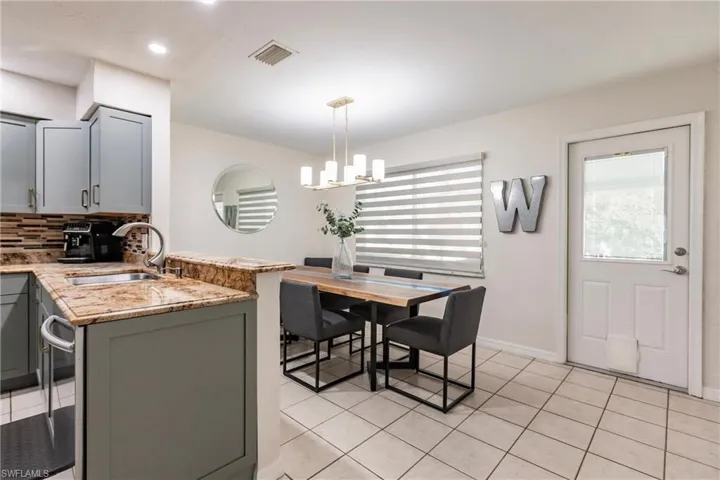 Kitchen featuring light stone counters, pendant lighting, gray cabinets, and kitchen peninsula