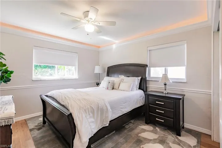 Bedroom with multiple windows, ceiling fan, crown molding, and dark hardwood / wood-style flooring
