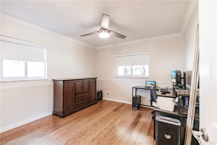 Office space featuring light wood-type flooring, crown molding, and ceiling fan