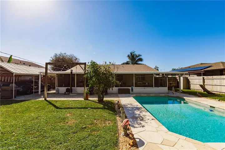 Back of property featuring a patio, a sunroom, a fenced in pool, and a lawn