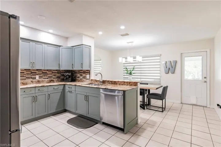 Kitchen featuring sink, kitchen peninsula, appliances with stainless steel finishes, and decorative light fixtures