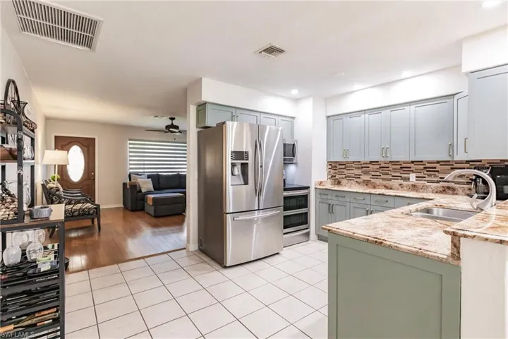 Kitchen with ceiling fan, light hardwood / wood-style flooring, sink, decorative backsplash, and appliances with stainless steel finishes