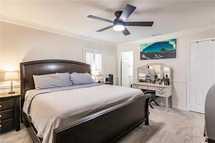 Carpeted bedroom featuring crown molding and ceiling fan