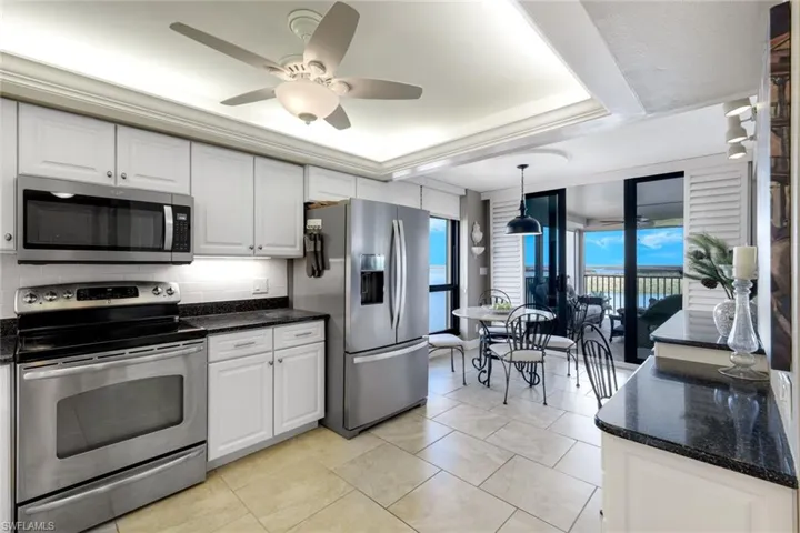 Kitchen featuring stainless steel appliances, white cabinets, decorative light fixtures, and tasteful backsplash
