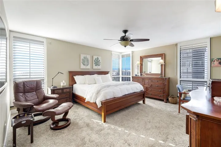 Bedroom with light colored carpet, ceiling fan, and multiple windows