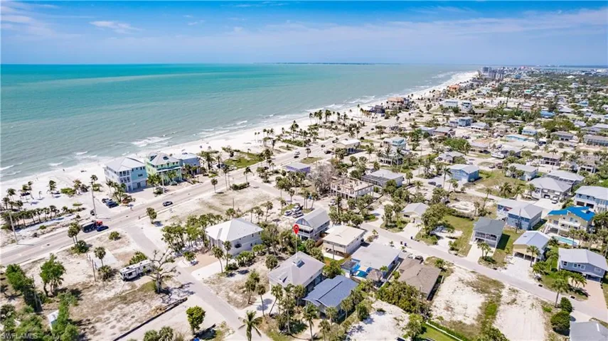 Birds eye view of property with a water view and a beach view
