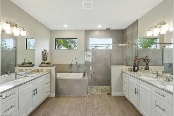 Dual shower heads including ceiling-mounted rainshower fixture. Soaking tub. Dual vanities with Fantasy Brown quartzite.