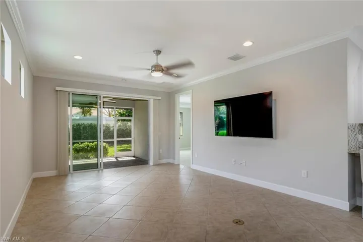 Great room view, tile flooring, crown molding, sliders opening to private lanai. TV does not convey.
