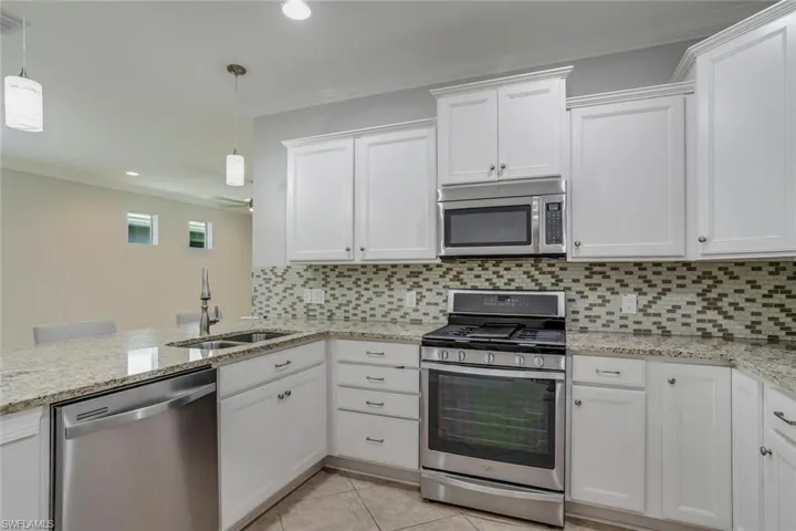 Granite counters with seating - bar stools included - stainless steel appliances, tile backsplash, pantry, upgraded lighting.