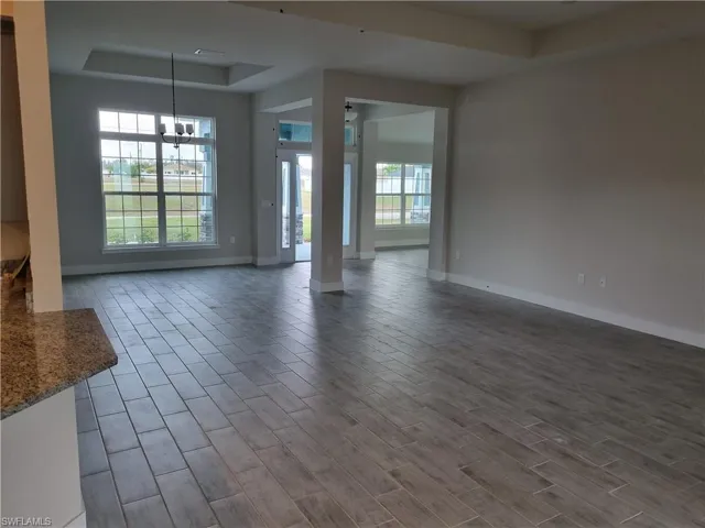 Unfurnished living room featuring a tray ceiling and wood finish floors