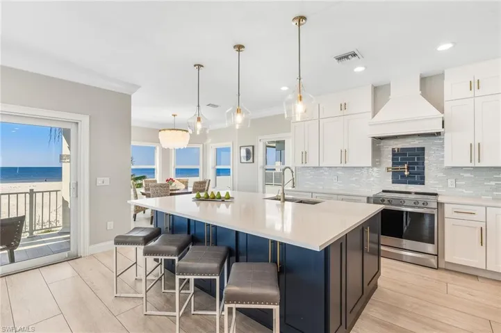 Kitchen with electric stove, white cabinetry, premium range hood, decorative backsplash, and decorative light fixtures