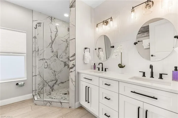 Bathroom featuring double vanity and a marble finish shower