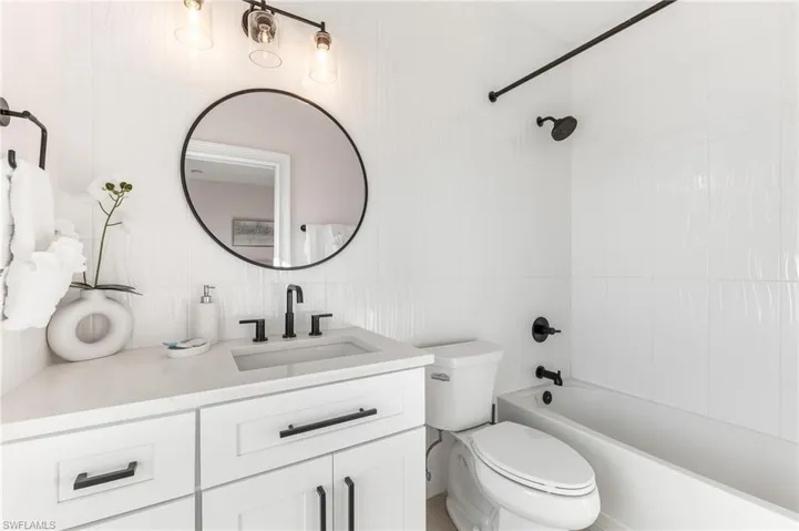Full bath with vanity, shower / tub combination, and tile walls