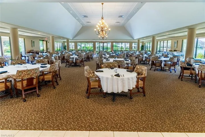 Clubhouse, carpeted dining room featuring high vaulted ceiling and a chandelier