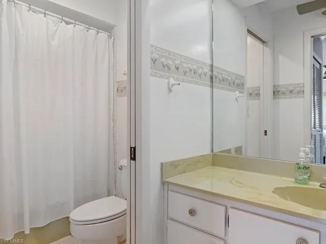 Bathroom featuring vanity, toilet, and curtained shower