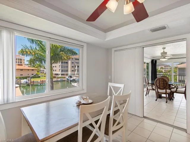 Dining area with a raised ceiling, a water view, ceiling fan, and tile patterned floors
