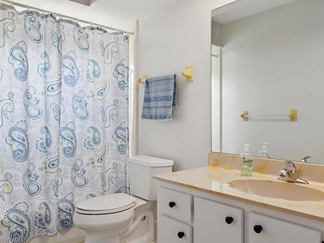 Bathroom featuring a shower with shower curtain, toilet, and vanity