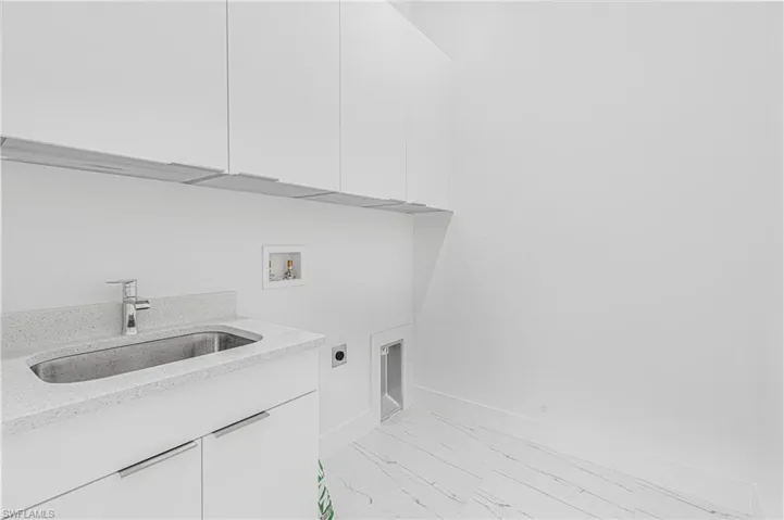 Washroom featuring electric dryer hookup, cabinet space, hookup for a washing machine, and light marble finish flooring
